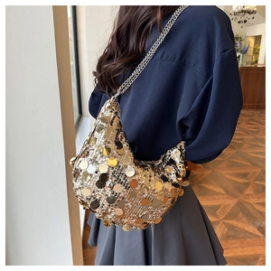 Detail view of a gold sequin crossbody bag with metallic silver chain strap on model