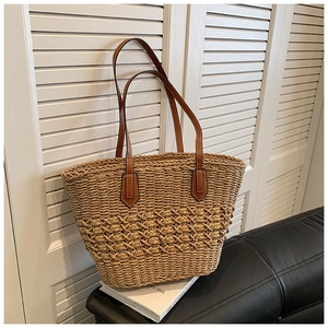 Sac fourre-tout en paille tissé à la main avec anses en cuir marron sur un canapé
