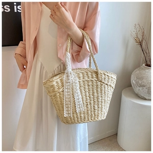Detail of woven straw tote bag with white lace ribbon trim and natural texture