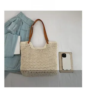 Detail view of cream knit tote bag featuring premium brown faux leather handles and rivets