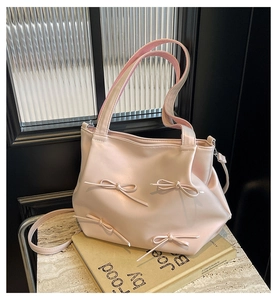 Close-up of pink PU leather tote bag featuring elegant bow knots and pleated drawstring detail