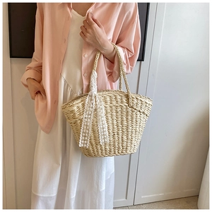 Detail of handmade beige straw tote bag featuring white lace ribbon and woven handles