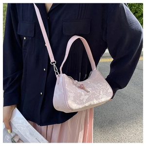 Detail of light pink moon-shaped bag with white butterfly prints and beaded charm strap