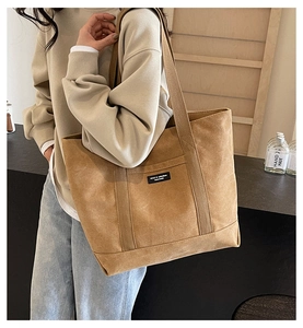 Detailed side view of a minimalist tan canvas tote bag worn by a model for daily use