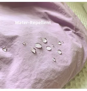 Détail du tissu en nylon hydrofuge avec des gouttelettes d'eau sur le sac bandoulière