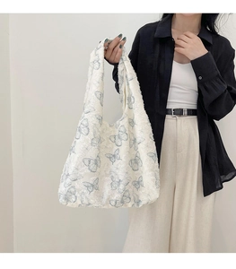 Detail of lace texture and blue butterfly print on a white tote bag held by model