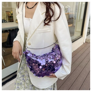 Detail of purple sequin half-moon bag with silver chain strap worn by a female model