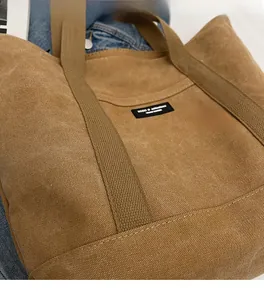 Detail shot of khaki canvas tote bag with black label on denim background