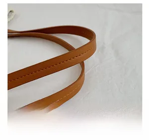 Detailed close-up of brown synthetic leather shoulder strap with neat stitching craft