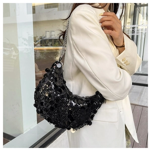Detail of black sequined crescent bag with silver chain strap on a white blazer