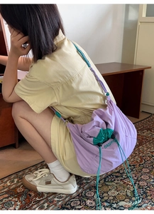 Détail du sac bandoulière léger en nylon avec fermeture par cordon et design de couleurs contrastées
