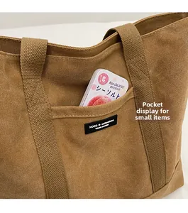 Detail view of the canvas tote bag front pocket with brand label and durable texture