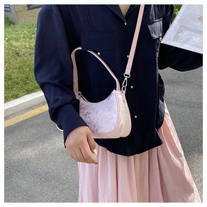 Detail view of pink crescent bag with jacquard texture and adjustable shoulder strap