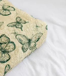 Detail of elegant lace fabric with butterfly patterns and soft textured feathers on a bag