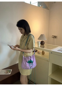 Détail du sac bandoulière en nylon violet avec cordon vert et bandoulière tissée