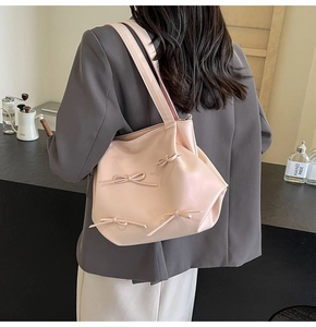 Detail of light pink PU leather tote bag with stylish 3D bow accents on casual strap