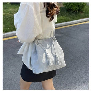Détail d'un sac seau gris clair montrant la texture PU plissée et l'anneau en métal doré
