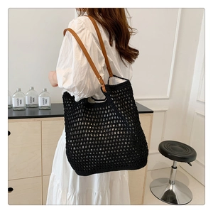 Detail of hand-woven black knit tote bag with brown leather shoulder straps