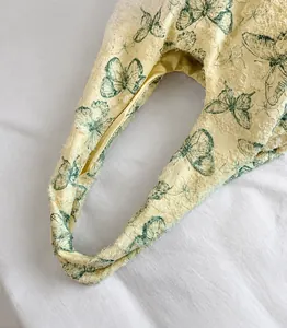 Close-up of cream lace handbag featuring blue butterfly print and textured raw edges