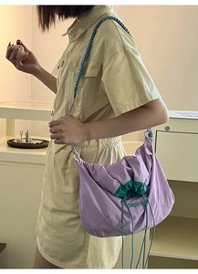 Détail du sac à cordon en nylon violet clair avec broderie verte et bandoulière