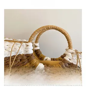 Close-up of circular woven handle on dual-tone straw tote bag showing craft texture