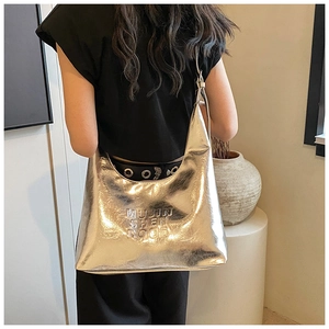 Borsa hobo argento metallizzato con lettere a rilievo mostrata in un set elegante