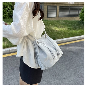 Détail du sac à bandoulière gris clair à franges avec texture plissée sur mannequin