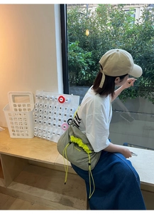 Détail du sac bandoulière en nylon gris avec cordon vert et logo de marque clabing