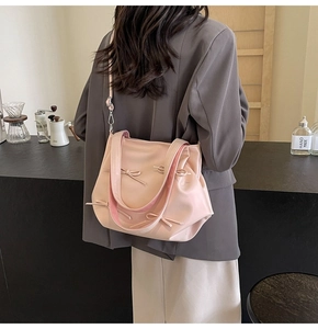Detailed close-up of pink PU leather tote bag with decorative bows in a cafe setting