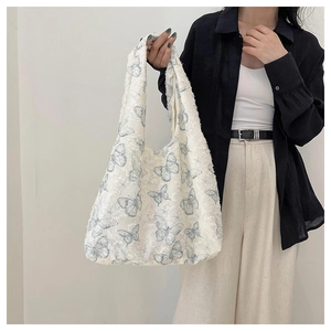 Detail of white tote bag featuring blue butterfly embroidery and textured lace fabric