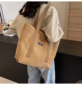 Detail of a large brown suede tote bag with a front pocket and stylish brand label
