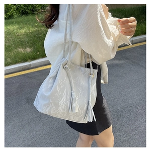 Détail du sac seau plissé argenté avec de longues franges et une fine bandoulière