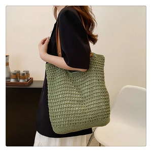 Detail of green knit tote bag featuring hollow mesh texture and brown leather straps