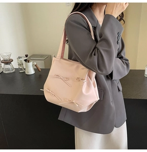 Pink PU tote bag with ribbon bows shown on model in a modern minimalist setting