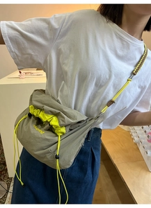 Détail du sac bandoulière en nylon vert olive avec broderie daping et bandoulière tressée