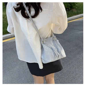 Détail du sac seau en cuir PU gris avec de longues franges et anneaux dorés