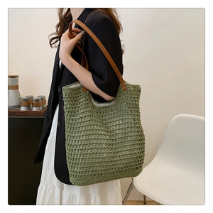 Detail of avocado green knit tote bag with brown leather handles and woven mesh texture