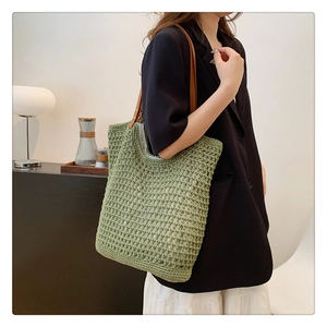 Detail of hand-woven green knit tote bag with premium brown leather handle and metal rivets