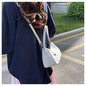 Detail view of a white fabric crossbody bag with lace texture and silver chain strap