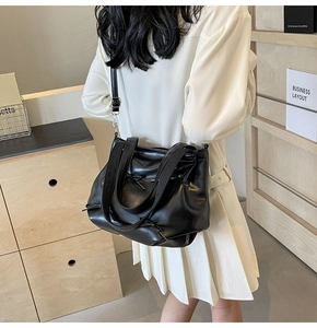 Close-up of black PU leather tote bag featuring pleated design and bow tie decoration
