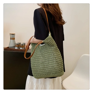 Detail of green knitted tote bag featuring a textured mesh pattern and brown leather straps