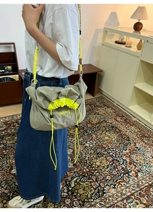 Détail du sac bandoulière en nylon olive avec cordon jaune fluo et logo de marque