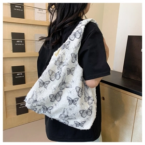 Detailed view of large white lace tote bag with black butterfly prints and integrated strap