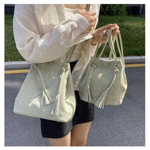 Détail de sacs seaux en similicuir vert clair en tailles large et petite avec pompons