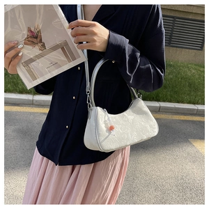 Detail of silver crescent crossbody bag featuring jacquard texture and bead charm accessory