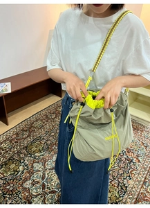 Détail du sac seau en nylon gris avec doublure jaune néon et bandoulière tressée