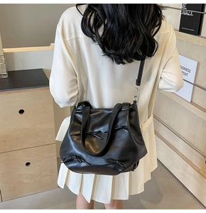 Detail of a black PU leather crossbody bag with decorative 3D bows and silver hardware