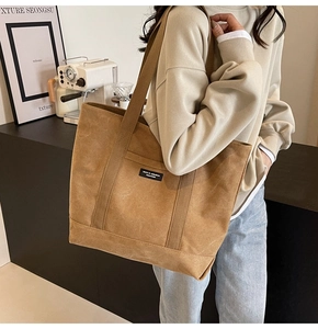 Detail of a brown canvas tote bag featuring NICO collections label and durable strap