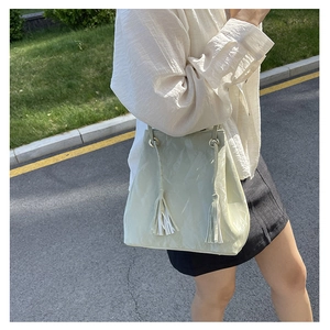 Détail du sac seau vert clair avec similicuir froissé et cordon de serrage à glands