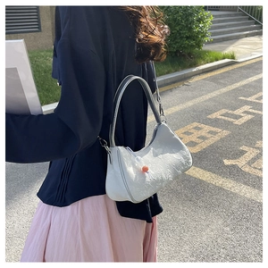 Detail of white jacquard crossbody bag with floral texture and bead pendant accessory